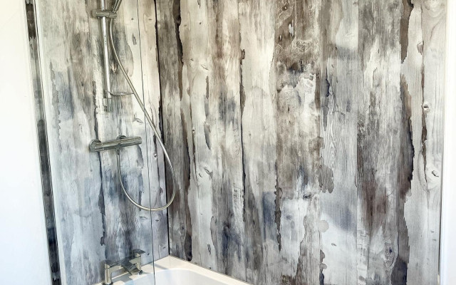 Beautifully crafted bathroom featuring a modern bath and stylish wood-effect wall design.